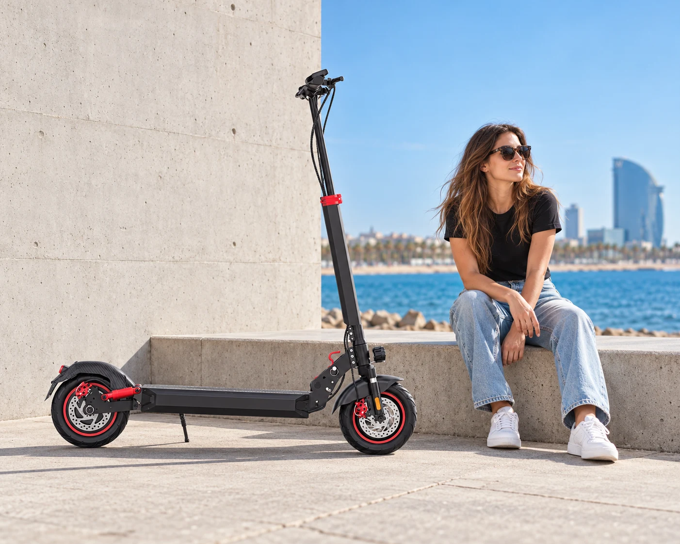 Una rider descansa junto a su patinete frente al mar en Barcelona
